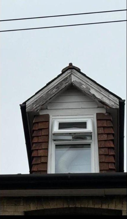 Rotten, peeling wooden fascia board on a dormer window before replacement, Reigate