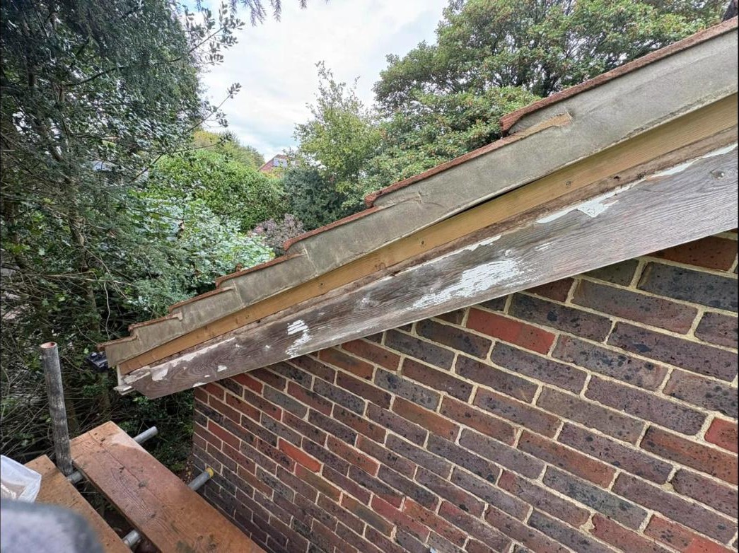 Rotten, peeling barge board timber on a roof gable before repair, Forest Row
